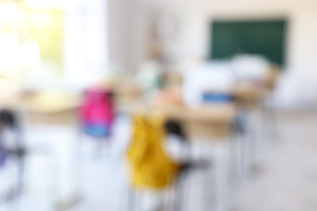 Blurred view of empty classroom with desks and blackboardの写真素材
