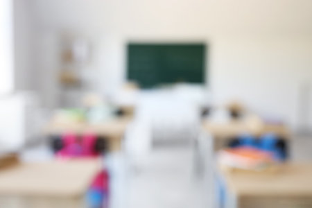Blurred view of empty classroom with desks and blackboardの写真素材