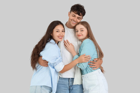 Young man with two women hugging on light background. Polyamory conceptの写真素材