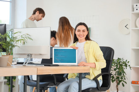 Female programmer with laptop at table in officeの写真素材