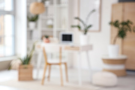Blurred view of light office with workplace, shelf unit and plantsの写真素材