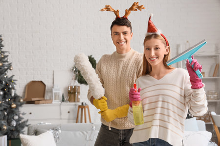 Young couple with cleaning supplies at home after New Year partyの写真素材