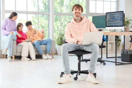 Tattooed male programmer working with laptop in office