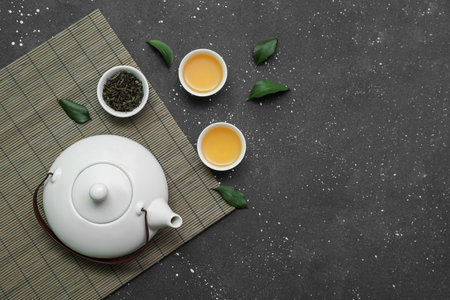Bowls and teapot of hot tea with dried leaves on black backgroundの写真素材