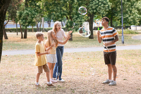 Happy family with cute children blowing soap bubbles in parkの写真素材