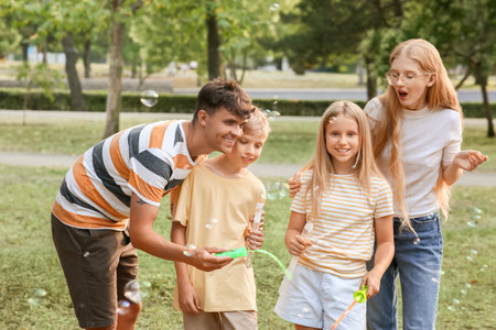 Happy family with cute children blowing soap bubbles in parkの写真素材