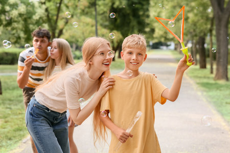 Happy family with cute children blowing soap bubbles in parkの写真素材