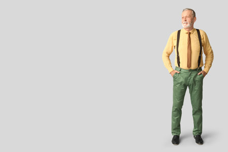 Handsome happy mature man with stylish tie on gray backgroundの写真素材