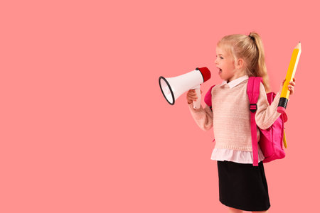 Cute little schoolgirl with big pencil and megaphone on pink backgroundの写真素材