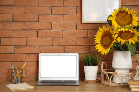 Comfortable workspace with bouquet of beautiful sunflowers and modern laptopの写真素材
