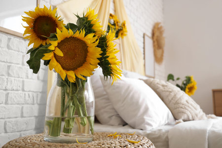 Vase with bouquet of beautiful sunflowers on bedside table, closeupの写真素材