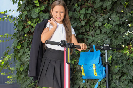 Cute schoolgirl with electric scooter outdoorsの写真素材