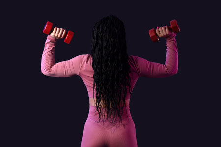 Female bodybuilder with dumbbells on dark background, back viewの写真素材