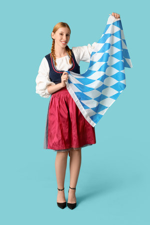 Beautiful happy Octoberfest waitress with Bavarian flag on blue backgroundの写真素材