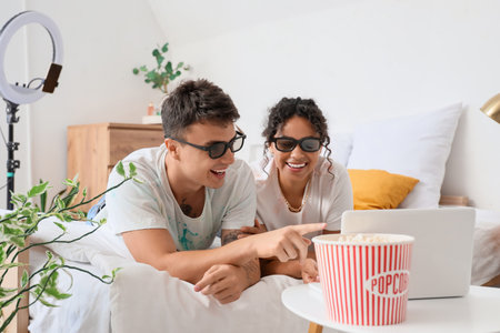 Couple of bloggers with popcorn recording review of movie in bedroomの写真素材