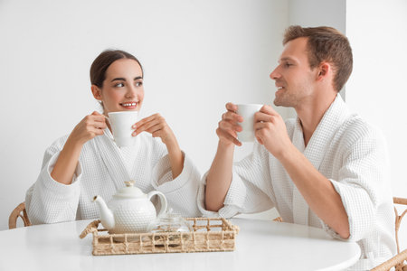 Young couple drinking tea at table after shower in kitchenの写真素材