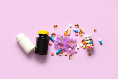 Plastic container with pills, bottles and scattered pills on lilac background. Top viewの写真素材