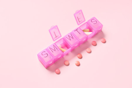 Plastic container with pills on pink background. Top viewの写真素材