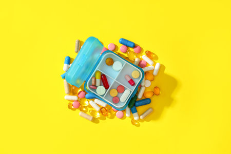 Blue plastic container with pills on yellow background. Top viewの写真素材