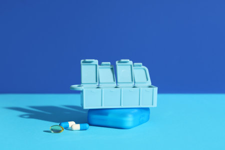 Plastic pill organizers on table against blue backgroundの写真素材