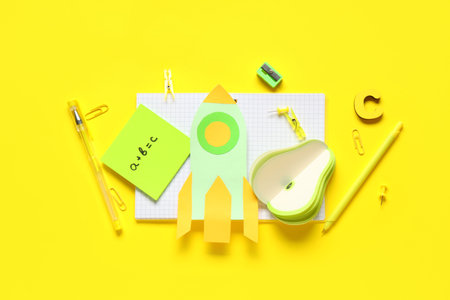 Paper rocket with school stationery on yellow background