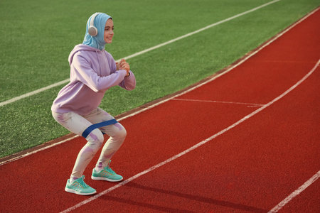Sporty Muslim woman in headphones training at stadiumの写真素材