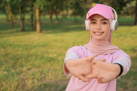 Sporty Muslim woman in headphones warming up in park, closeupの写真素材