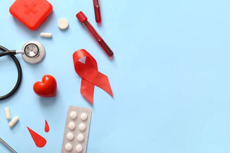 Red ribbon with stethoscope, pills, blood samples and paper drops on blue background. Blood Cancer Awareness Monthの写真素材