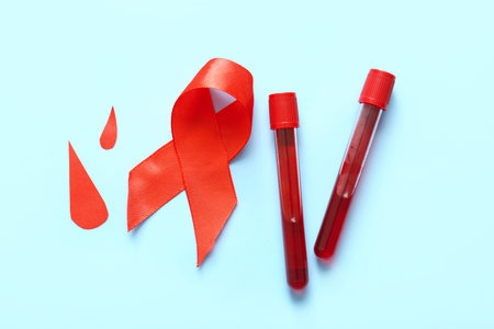 Red ribbon with samples and blood paper drops on blue background. Blood Cancer Awareness Month