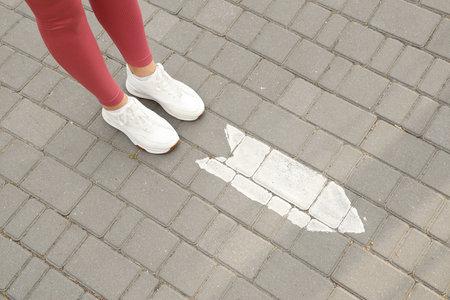 Woman standing on paved road with arrow marking. Concept of choiceの写真素材