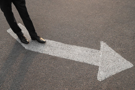 Businessman walking along road with arrow marking. Concept of career choice