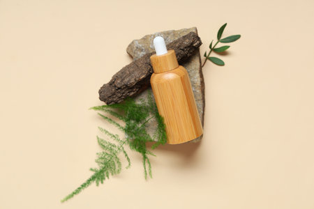 Composition with bottle of essential oil, stone and plant leaves on color backgroundの写真素材
