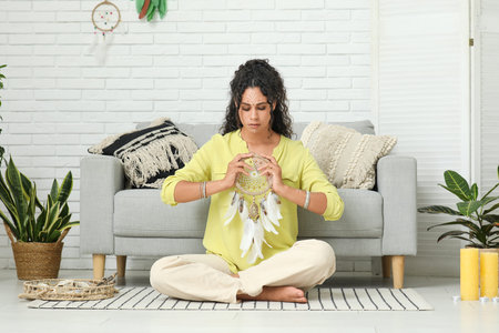 Beautiful African-American female shaman with dream catcher at home
