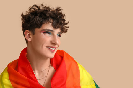 Young transgender woman with LGBT flag on beige background, closeup