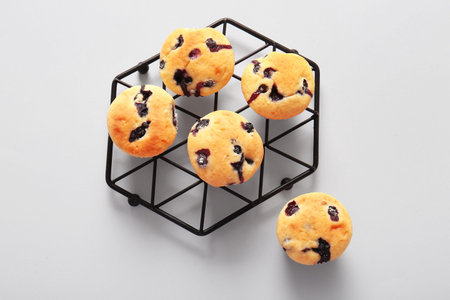 Cooling rack with tasty blueberry muffins on white background