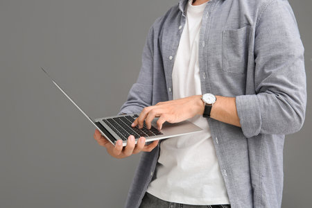 Male programmer using modern laptop on gray background, closeupの写真素材