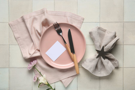 Stylish table setting with blank card and beautiful flowers on white tile backgroundの写真素材