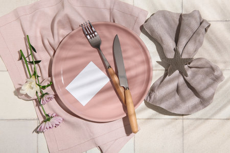 Stylish table setting with blank card and beautiful flowers on white tile backgroundの写真素材