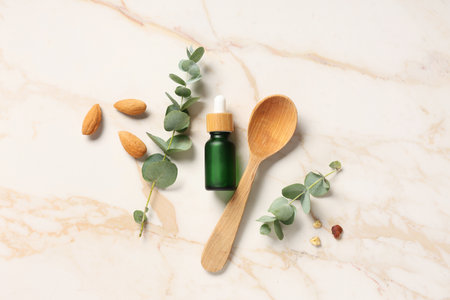 Nuts, wooden spoon and bottle of eucalyptus essential oil on marble backgroundの写真素材
