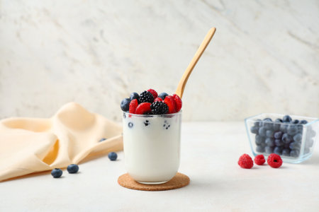 Glass of tasty yogurt with different fresh berries on white backgroundの写真素材