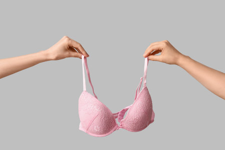 Female hands with stylish lace bra on gray background, closeupの写真素材