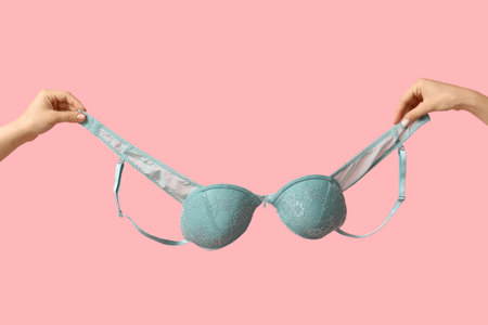 Female hands with stylish lace bra on pink background, closeupの写真素材