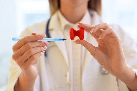 Female endocrinologist with thyroid gland model and pen in clinic, closeupの写真素材