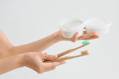 Young woman with jars of tooth powder and brushes on light background, closeupの写真素材