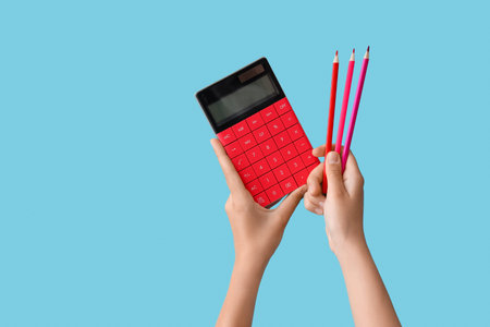 Female hands with calculator and pencils on blue background