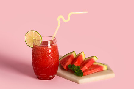 Glass of fresh watermelon juice with lime and mint on pink backgroundの写真素材