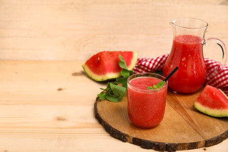 Glass and jug of fresh watermelon juice with mint on wooden backgroundの写真素材