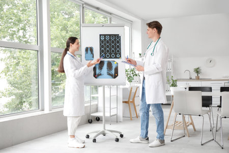Young doctors studying x-ray images on flipchart in clinic