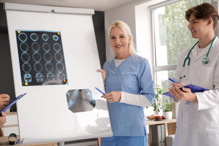 Doctors studying x-ray images on flipchart in clinic