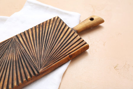 Wooden cutting board on beige background, closeup
